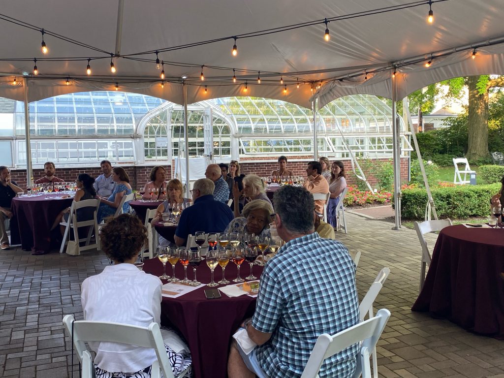 several tables of people with four wines to taste in front of each seat