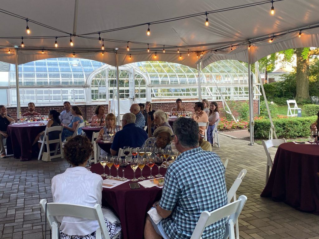 several tables of people with four wines to taste in front of each seat