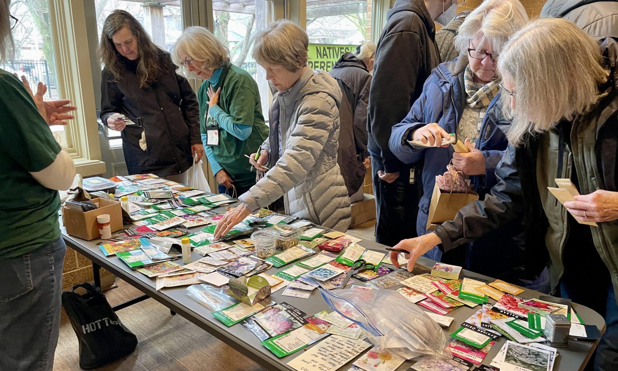 people gather around a table of seed packets to shop