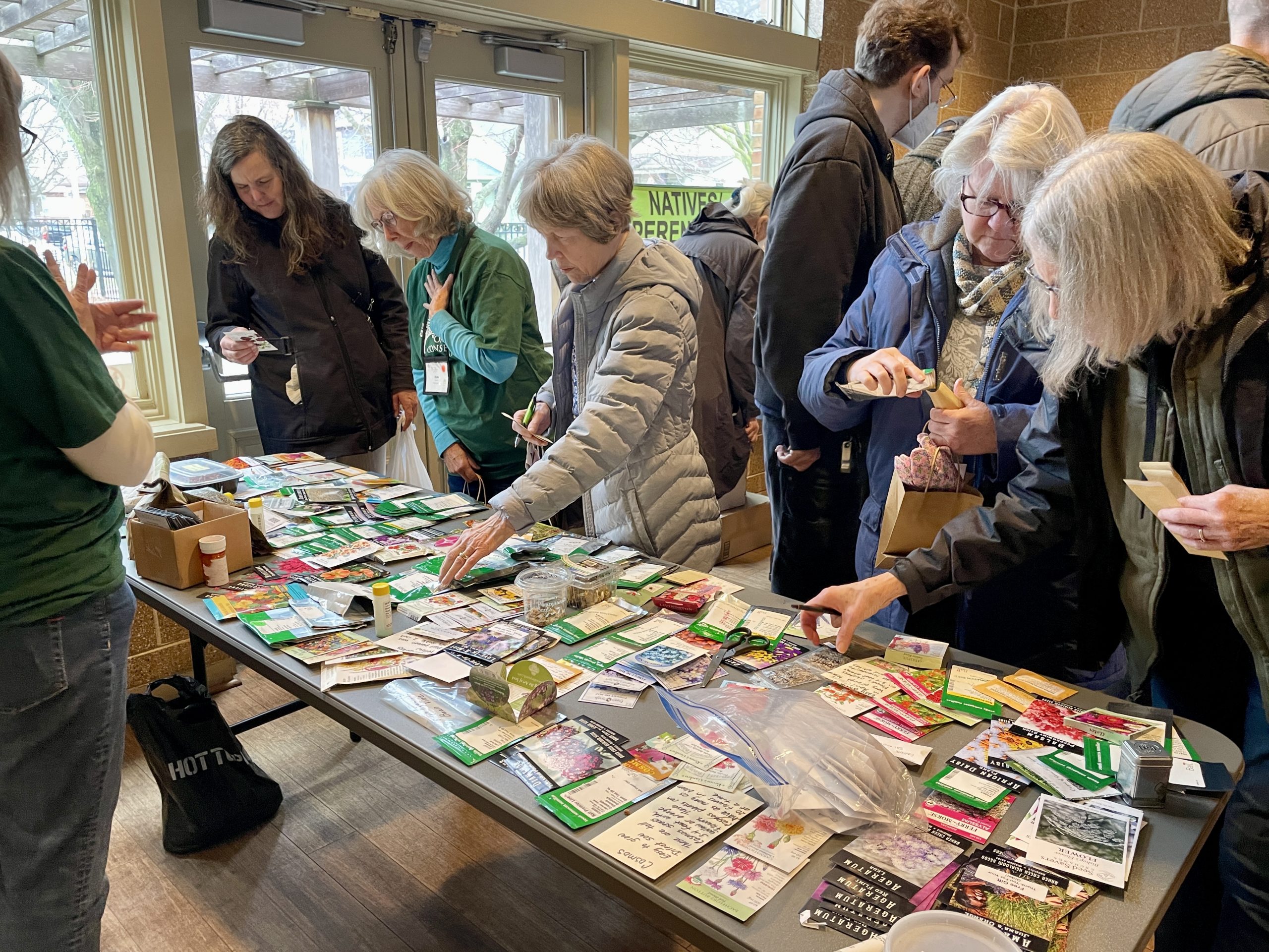 people gather around a table of seed packets to shop