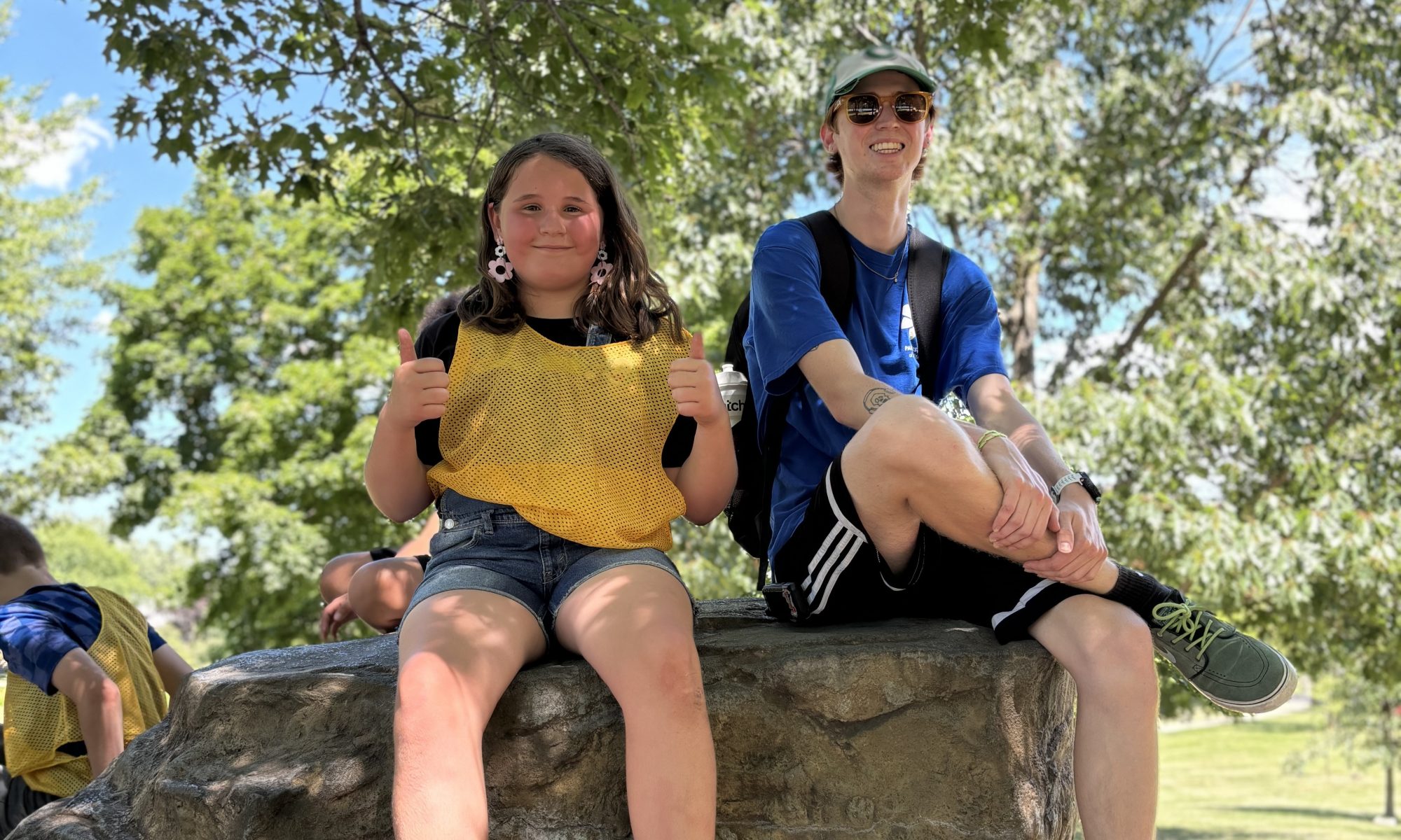 Camp counselor poses with camper on big rock