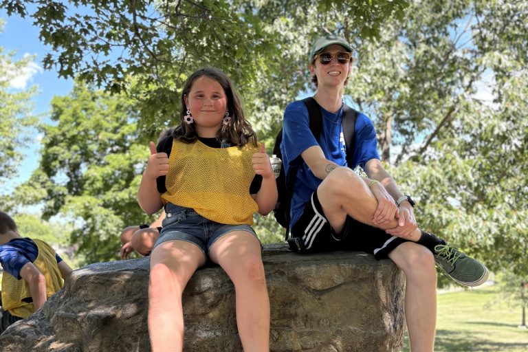 Camp counselor poses with camper on big rock