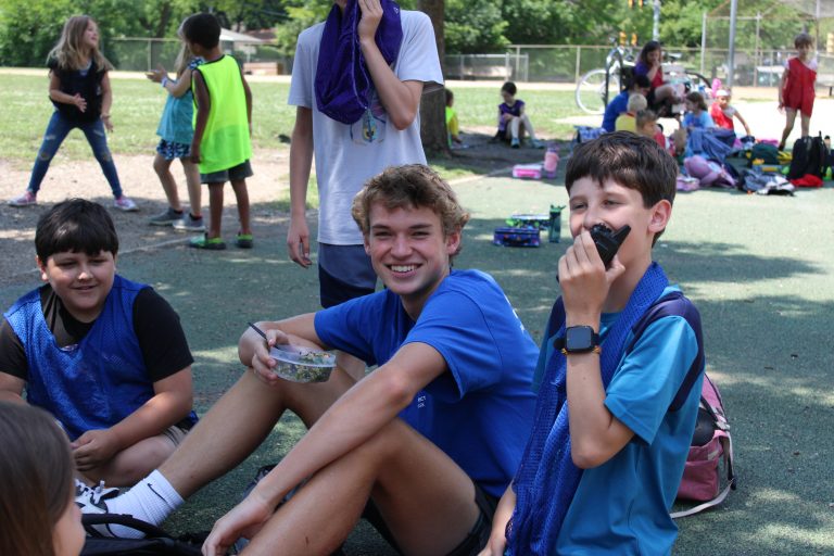 Camp counselor eats lunch with campers