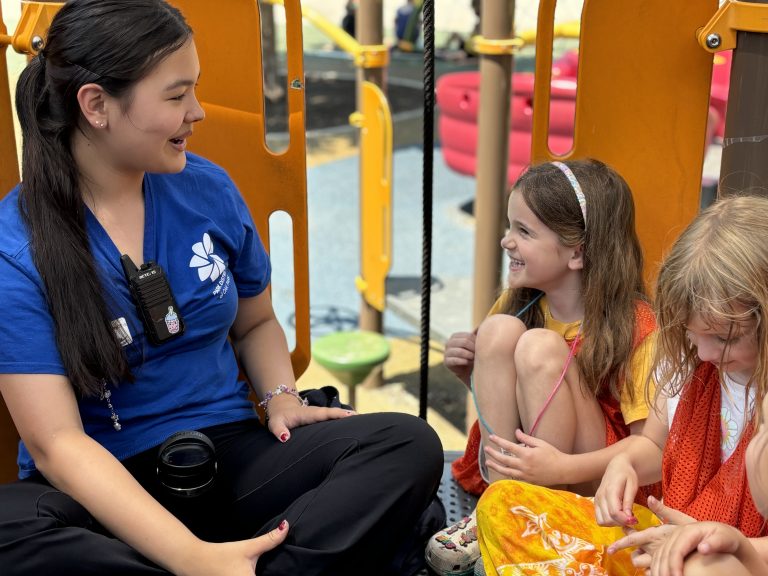 Camp counselor chats with campers on the playground