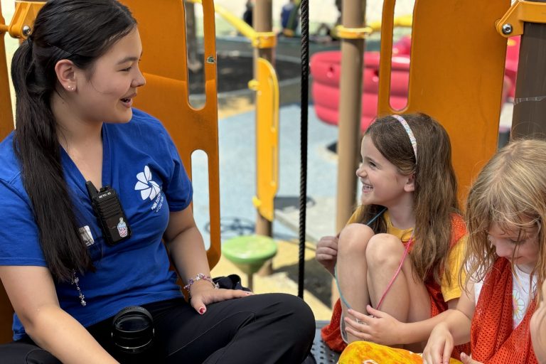 Camp counselor chats with campers on the playground