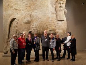 a group of lifelong learners pose in front of a large piece of artwork at a museum