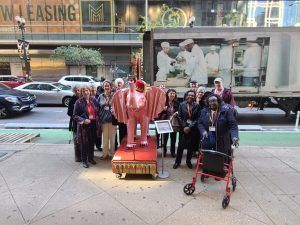 a group of lifelong learners pose by a sculpture of an elephant
