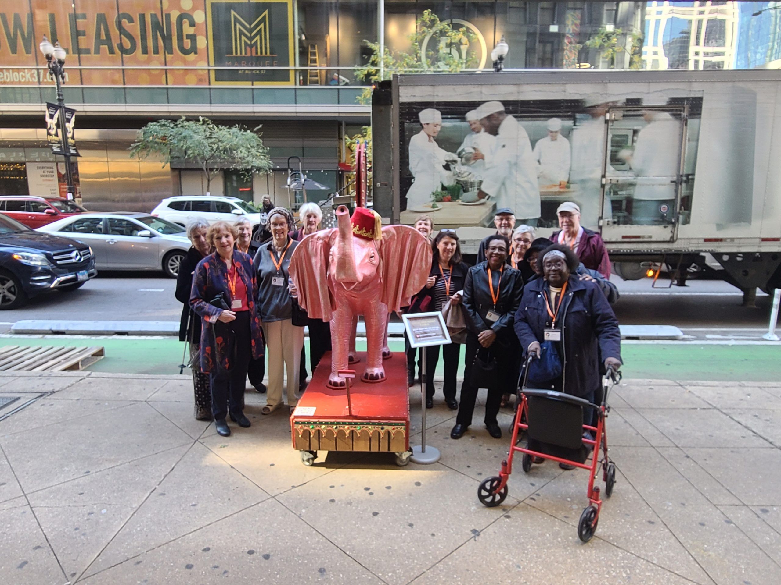a group of lifelong learners pose by a sculpture of an elephant