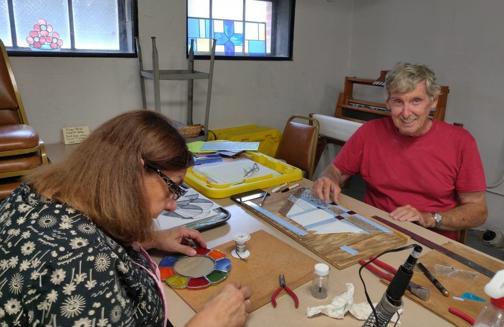 two adults work on stained glass projects