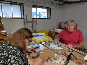 two adults work on stained glass projects