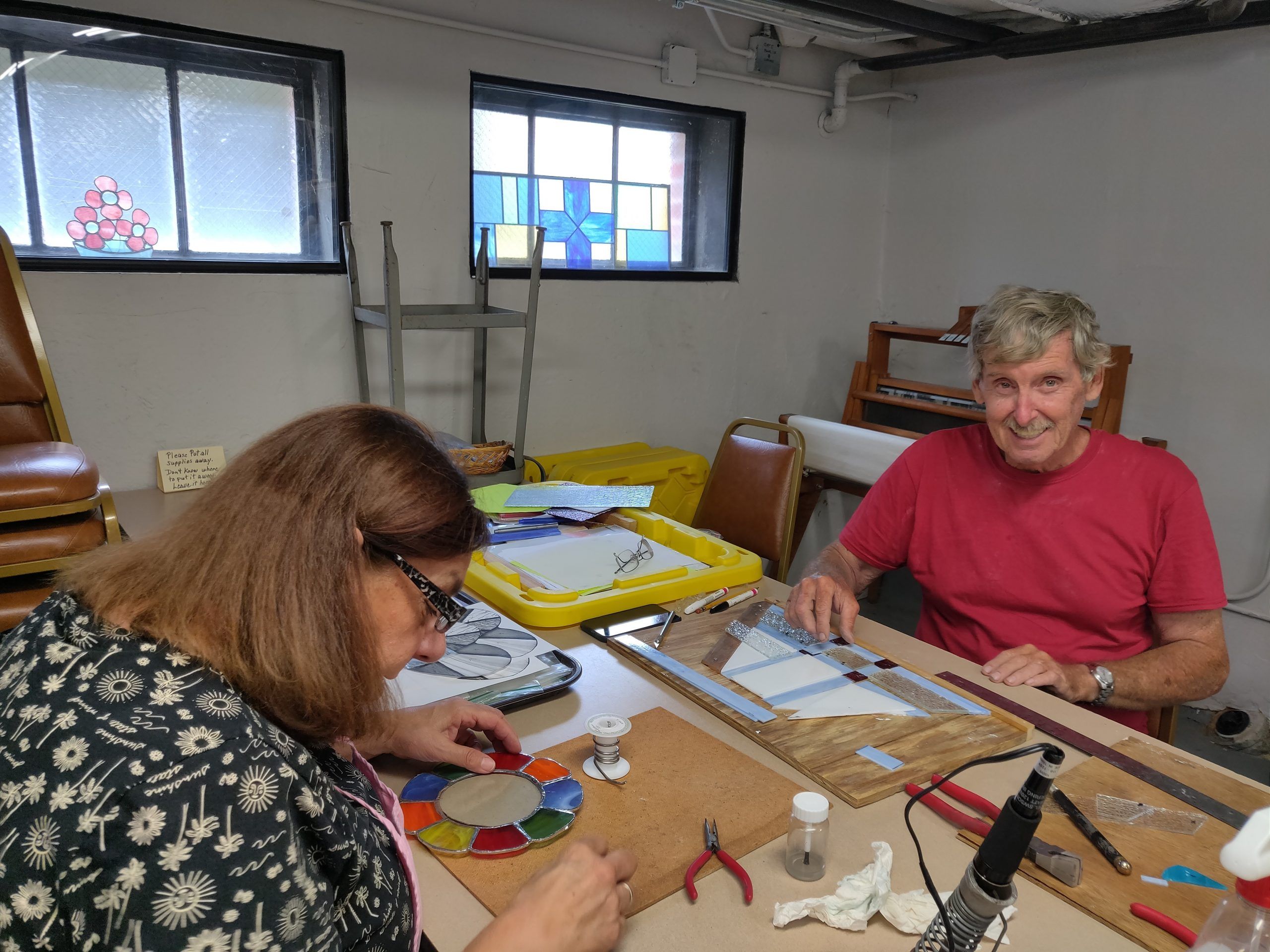 two adults work on stained glass projects