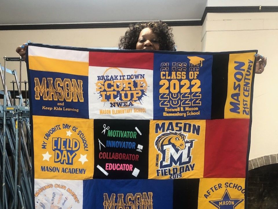 a woman holds up a quilt