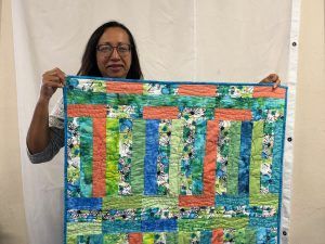 a woman holds up a quilt