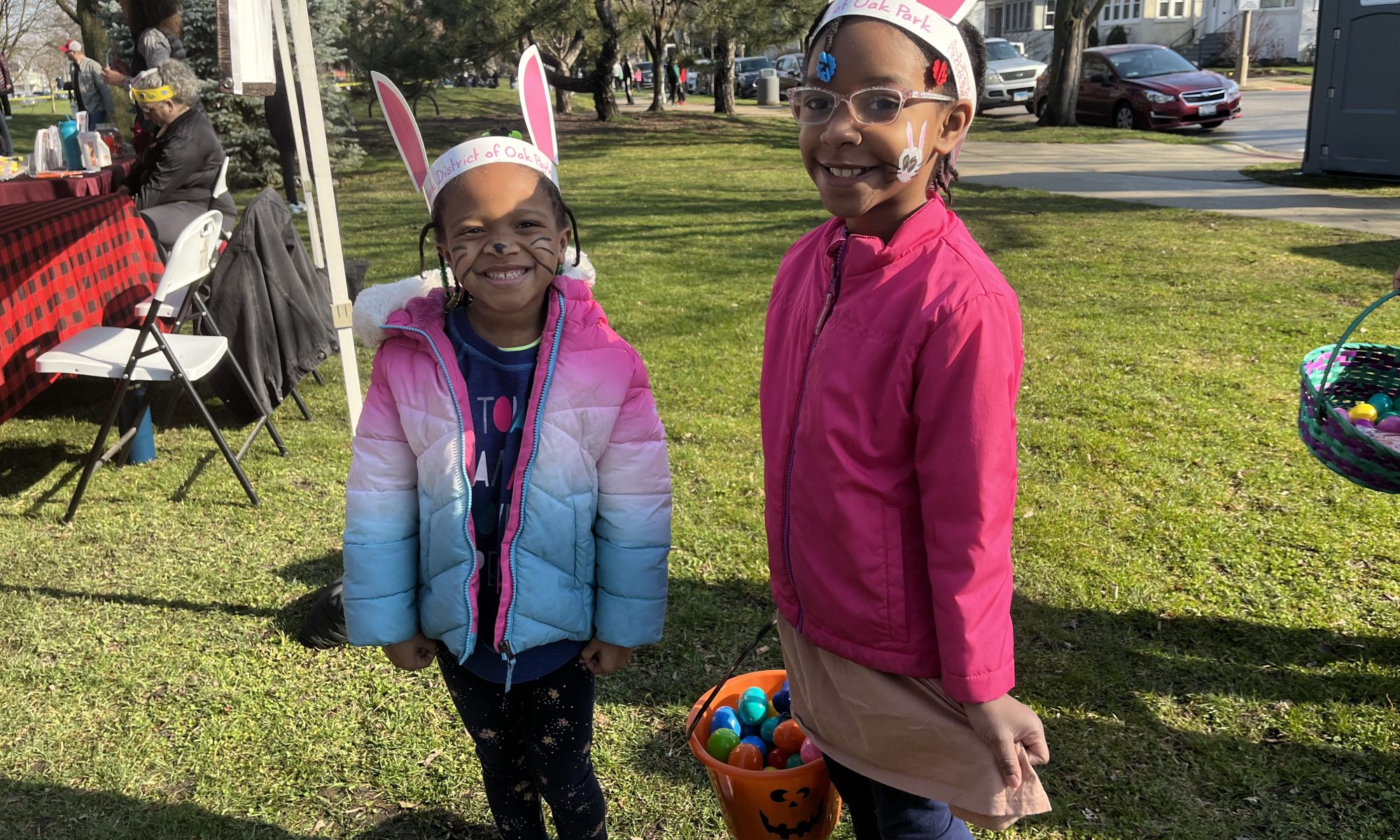 two girls wear bunny ears and hold their basket of eggs