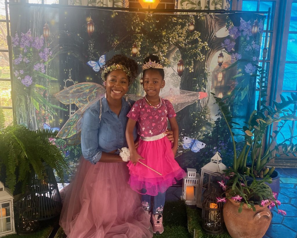 mom and daughter pose in front of fairy backdrop with tulle skirts on