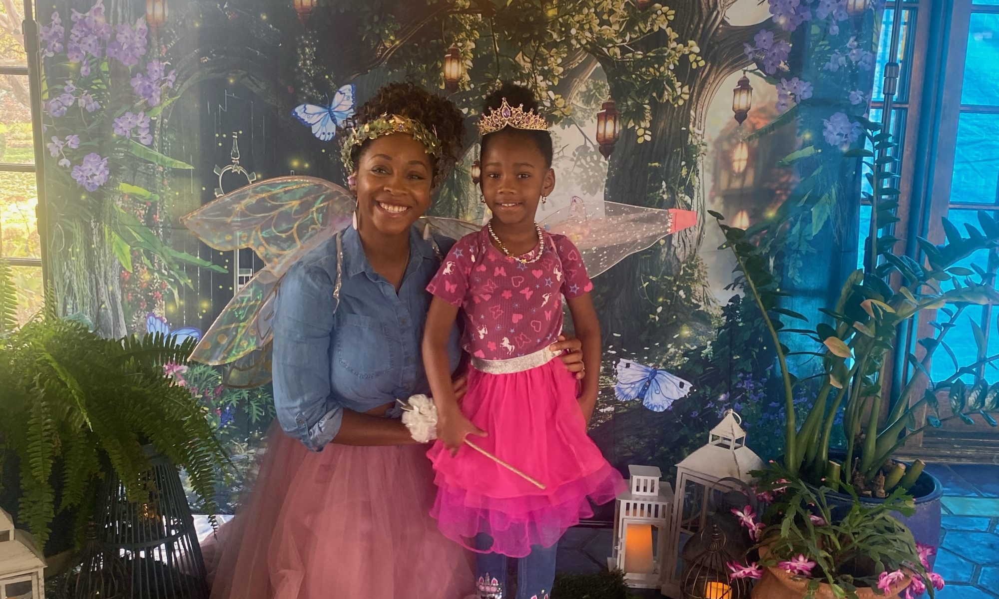 mom and daughter pose in front of fairy backdrop with tulle skirts on