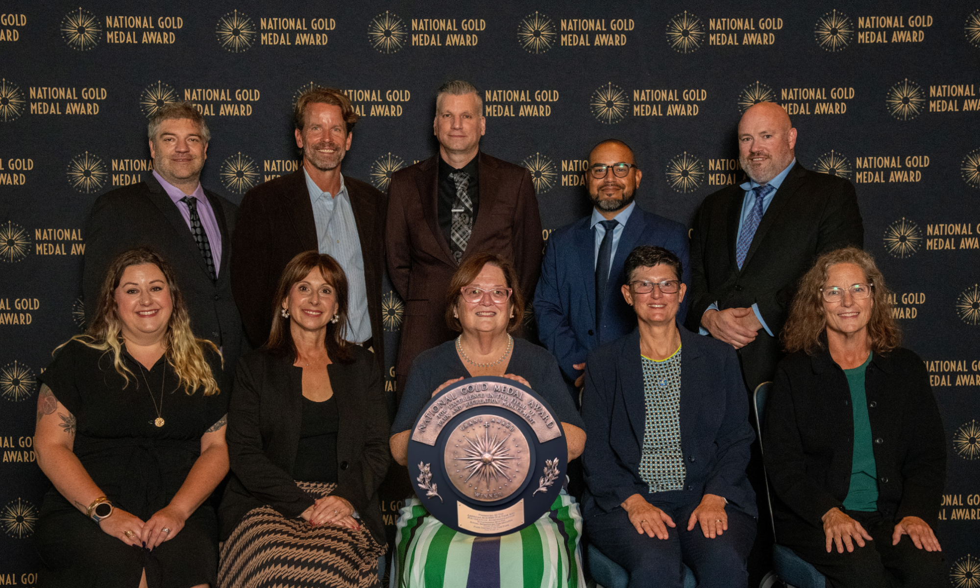park district board and staff members hold gold medal grand plaque