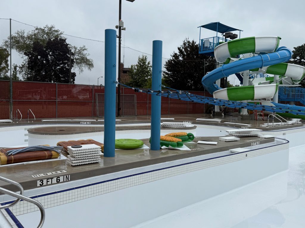 green, white, and blue waterslides, an empty pool basin, and the current channel in the background
