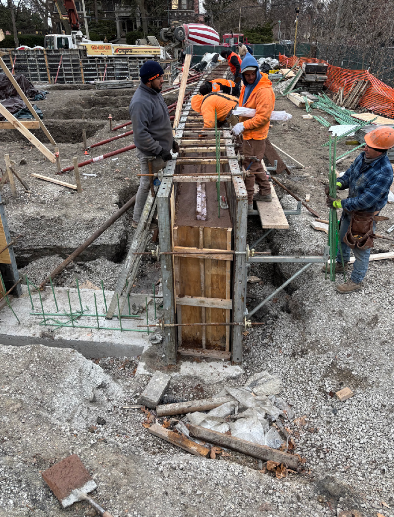 construction workers insert dowels into freshly poured walls