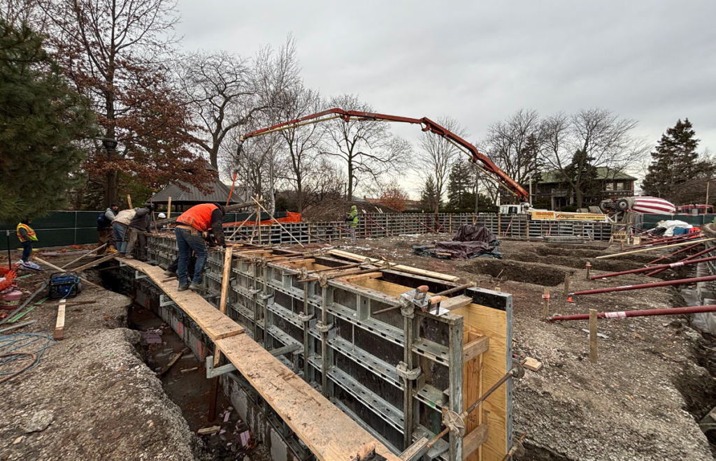 concrete truck with long arms deposits concrete into forms