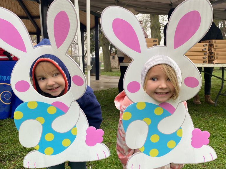two girls poke their heads through a bunny cutout