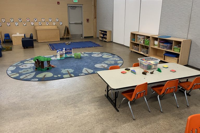 a large sitting rug with some toys and a table with magnatiles