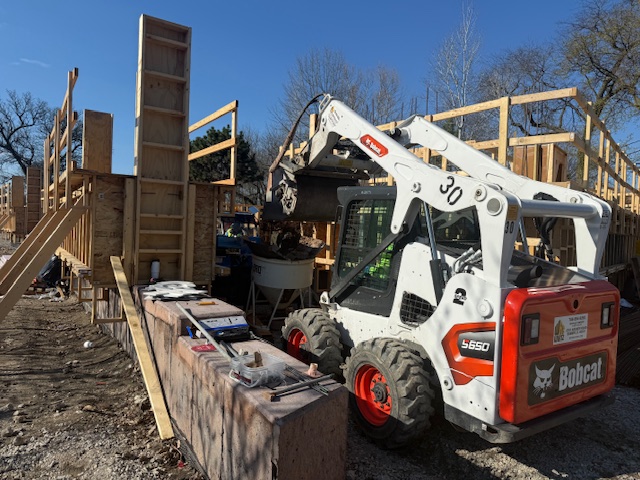 a white and red construction vehicle sits next to the building with its arm raised