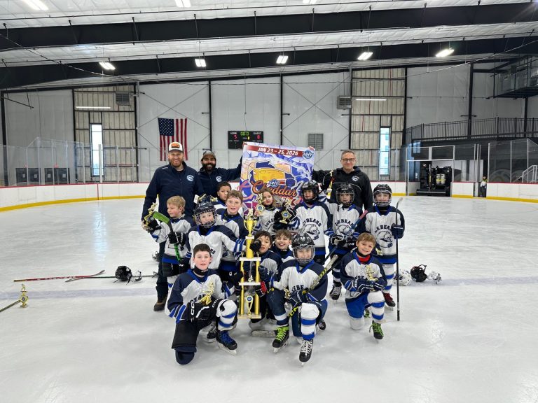 ice bears in white jerseys hold three tier trophy and smile