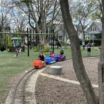 children sitting on orange, blue, and purple hand pedal train cars