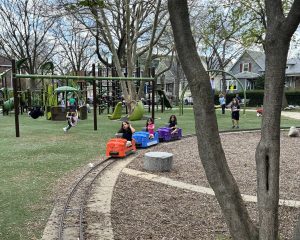 children sitting on orange, blue, and purple hand pedal train cars