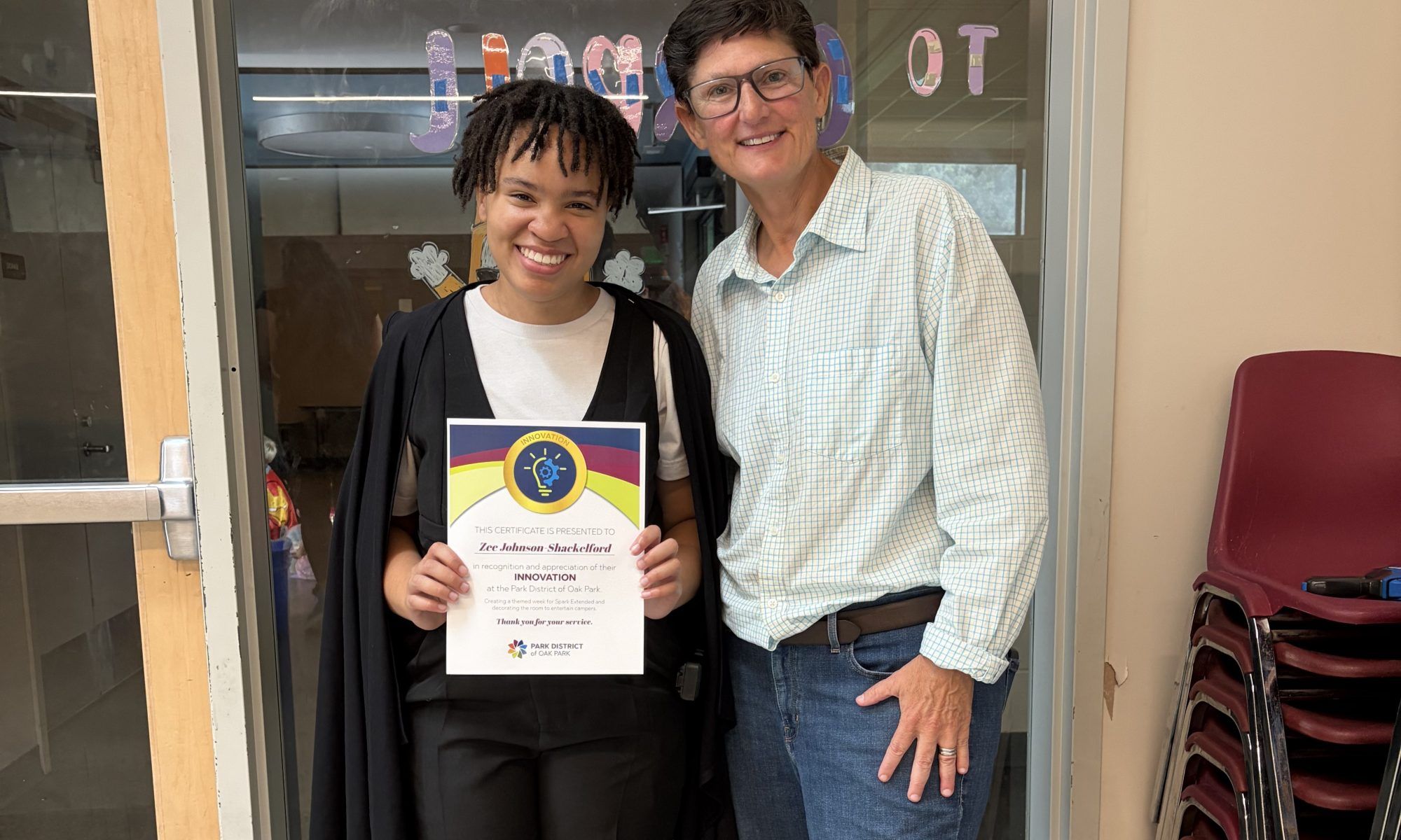 a counselor holds up their certificate while posing for a photo with the executive director