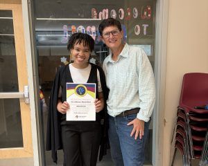 a counselor holds up their certificate while posing for a photo with the executive director